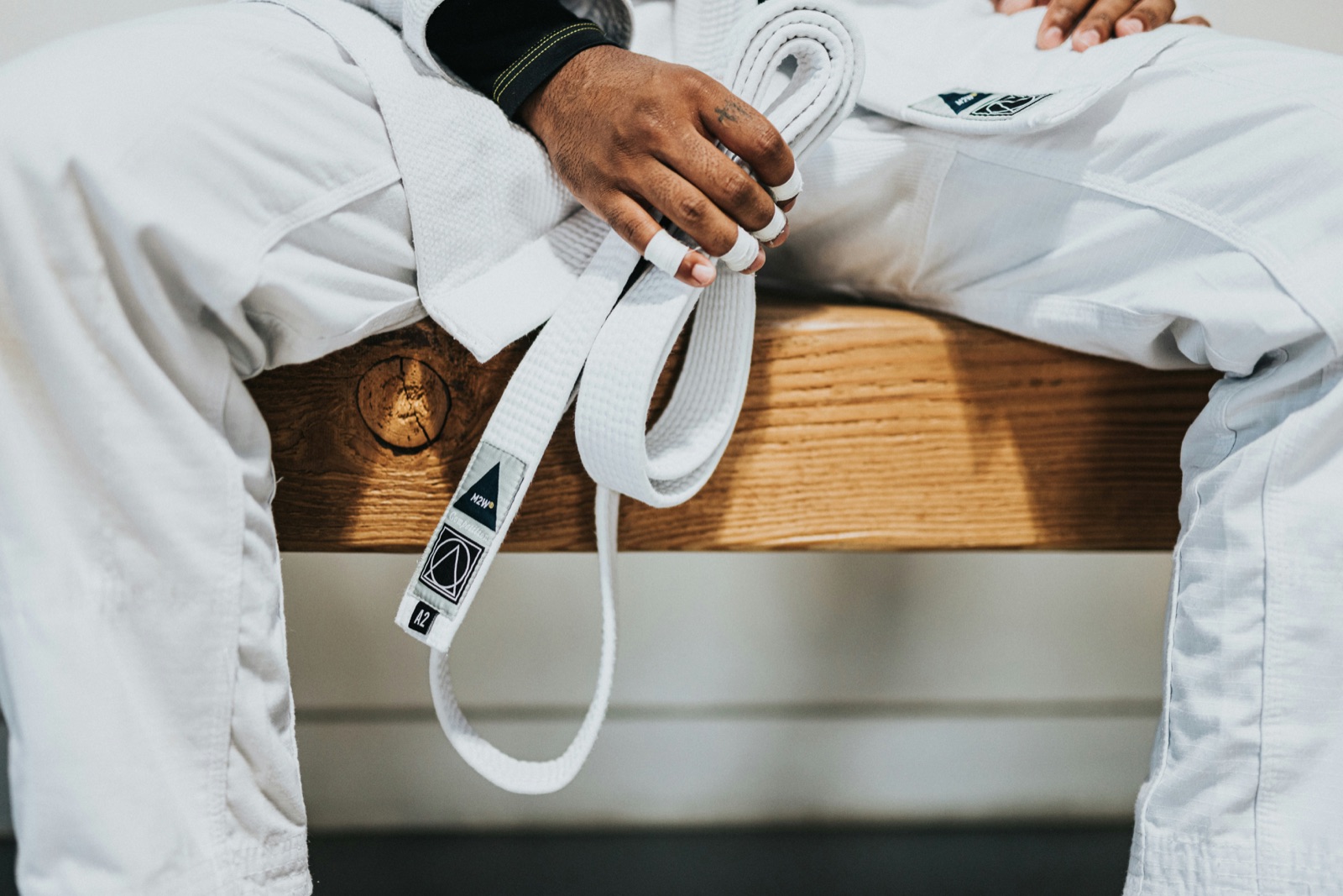 A jiu-jitsu practitioner in a white gi holding their belt between classes